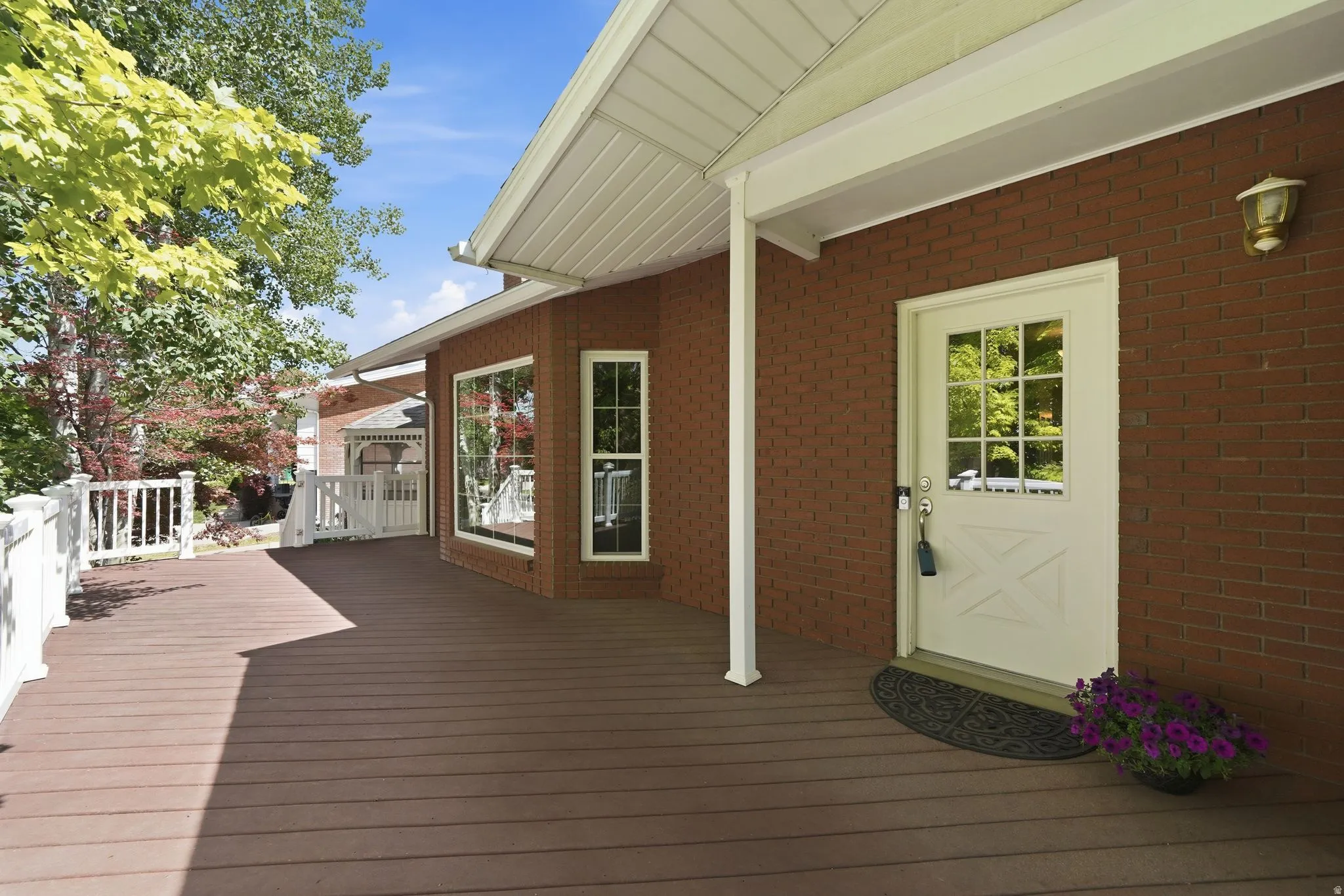 Spacious outdoor deck featuring wood-finish flooring, white railing, and a brick exterior