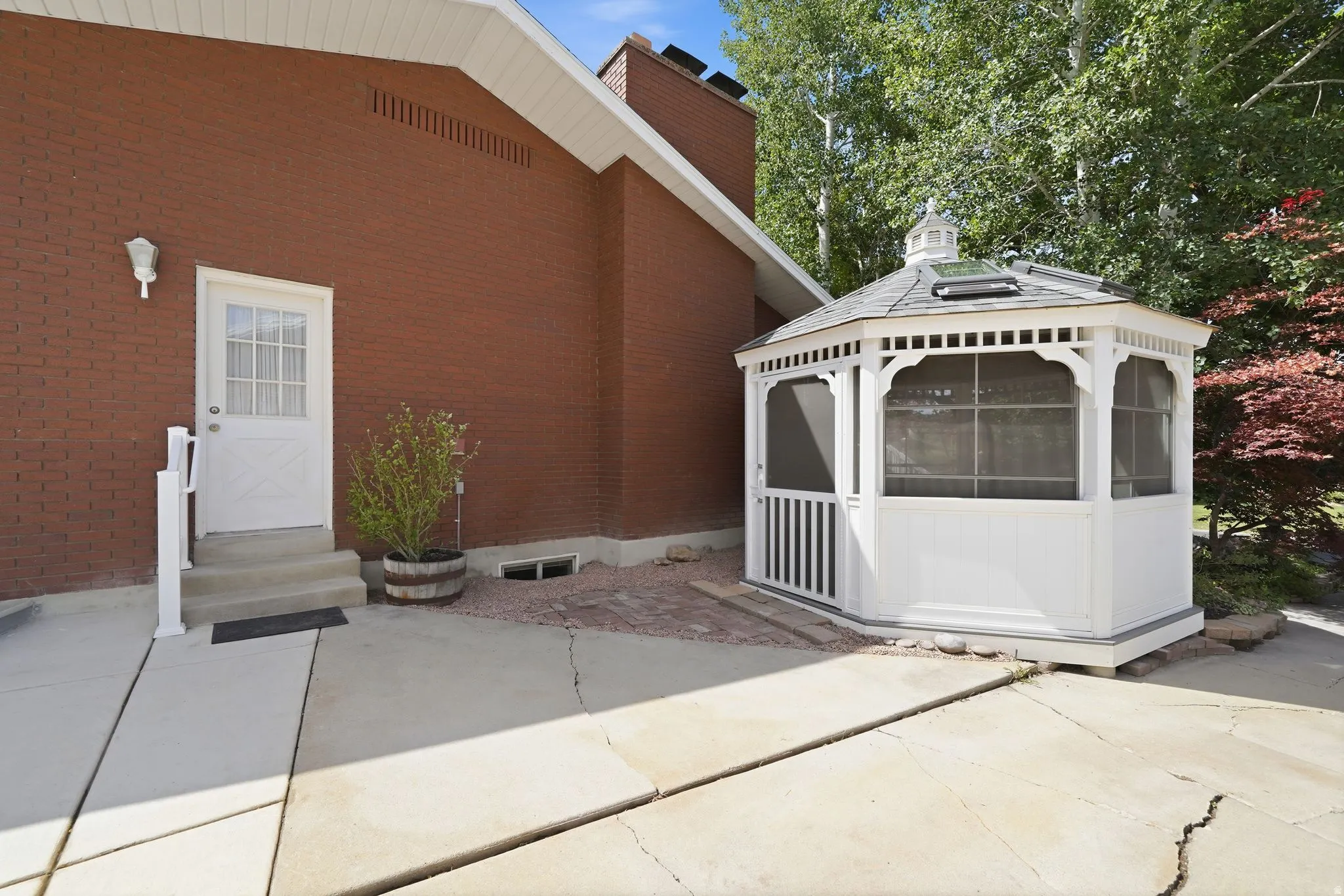 White screened gazebo with a gray-shingled roof and skylight