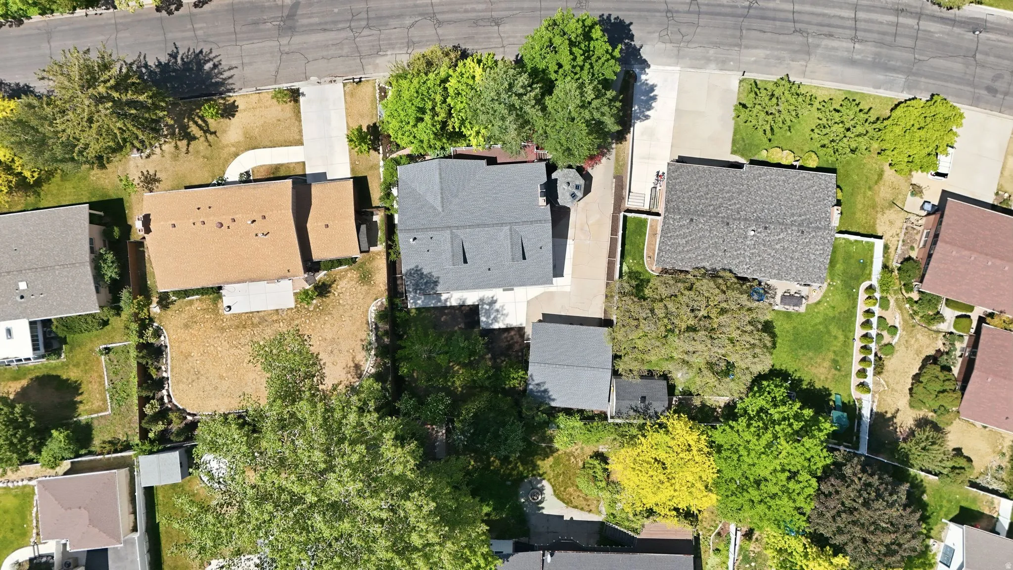 Property featuring a light brown shingle roof, a concrete driveway, and a partially landscaped backyard