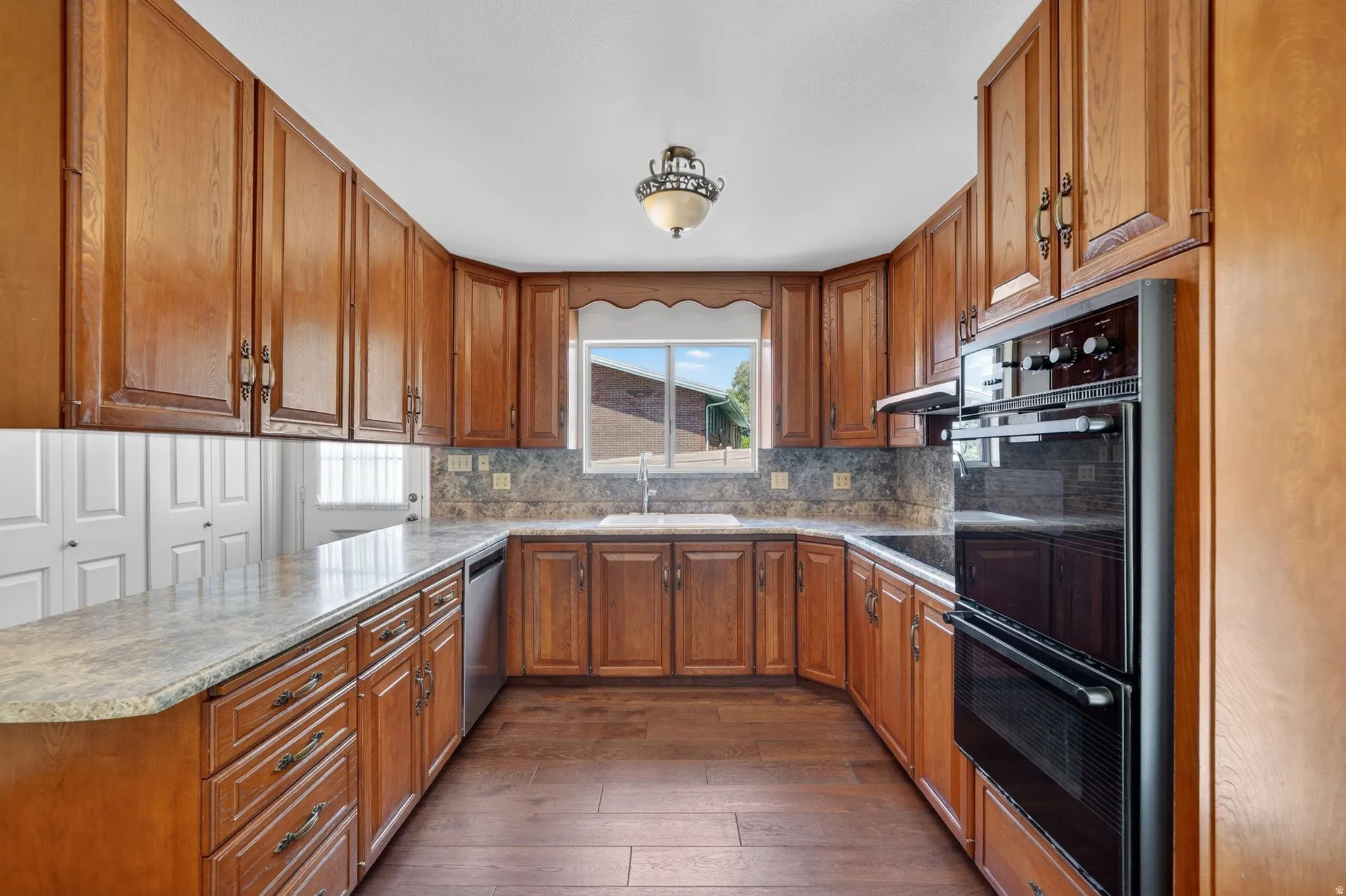 U-shaped kitchen featuring wood cabinetry, light-toned countertops, and a tile backsplash