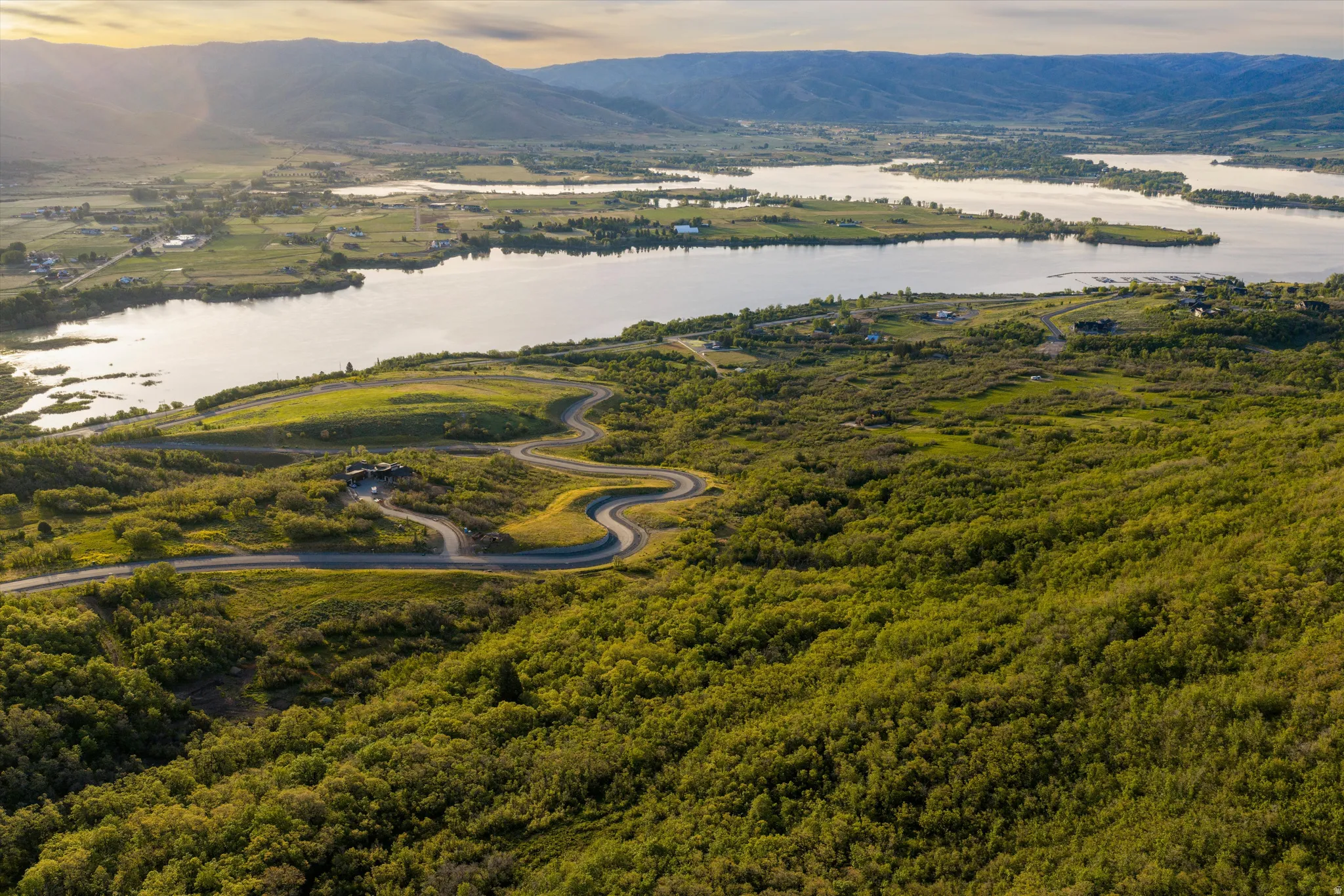 Winding paved road traversing a verdant landscape with extensive tree coverage