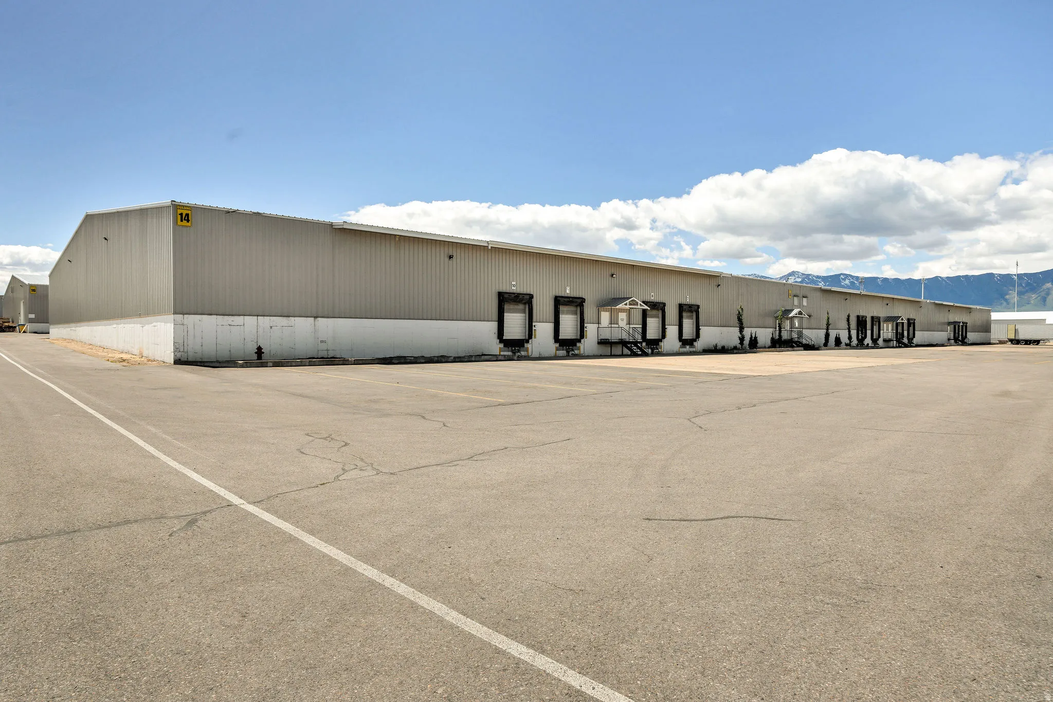 Industrial building featuring multiple loading docks, a substantial paved parking area, and a corrugated metal exterior