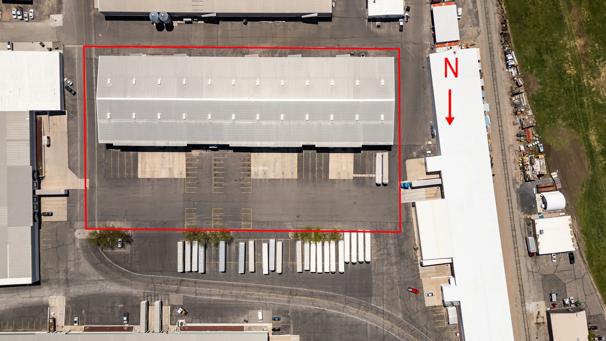 Expansive industrial property featuring a large warehouse building with a metal roof and multiple skylights