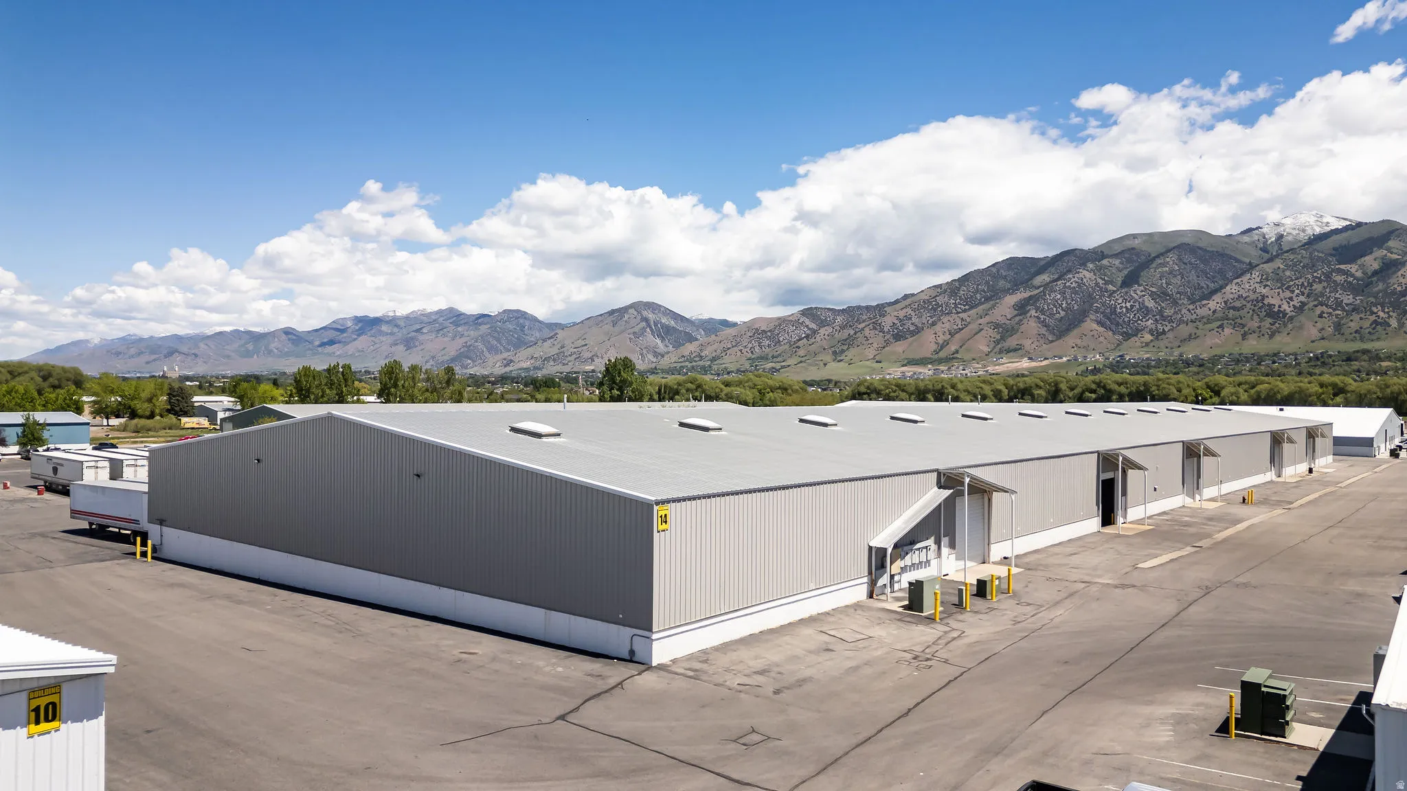 Industrial building with a metal facade, multiple dock-high doors, and a large paved lot