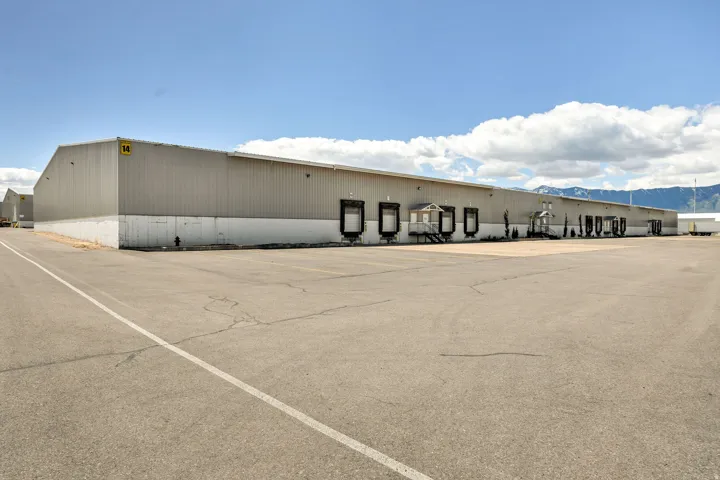 Industrial building featuring multiple loading docks, a substantial paved parking area, and a corrugated metal exterior