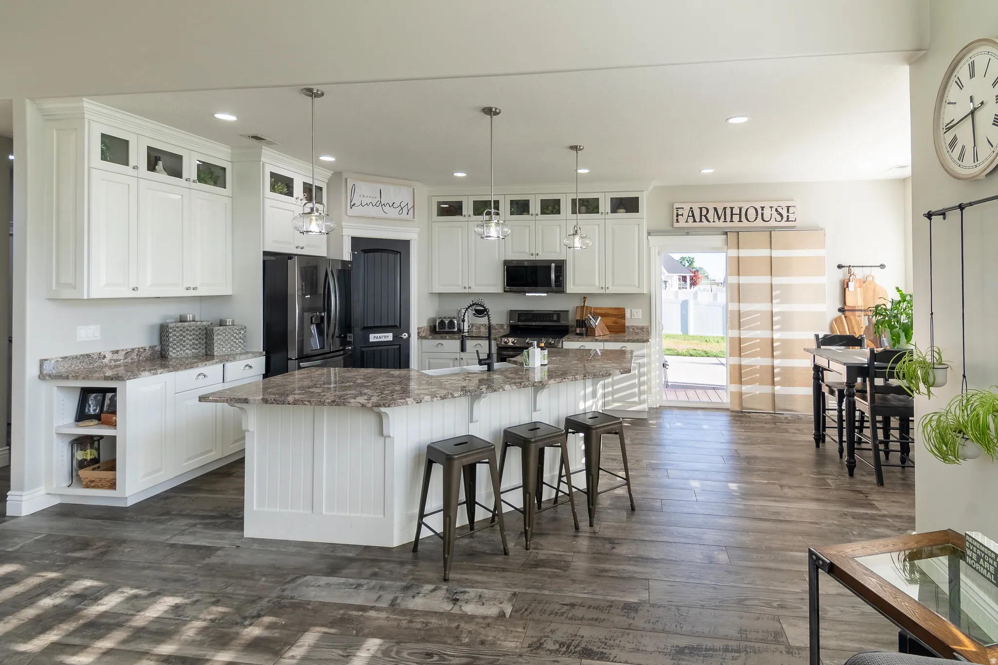 Kitchen featuring a central island with countertop seating, wood-finish flooring, white cabinetry, integrated appliances, and a glass-paned exterior door