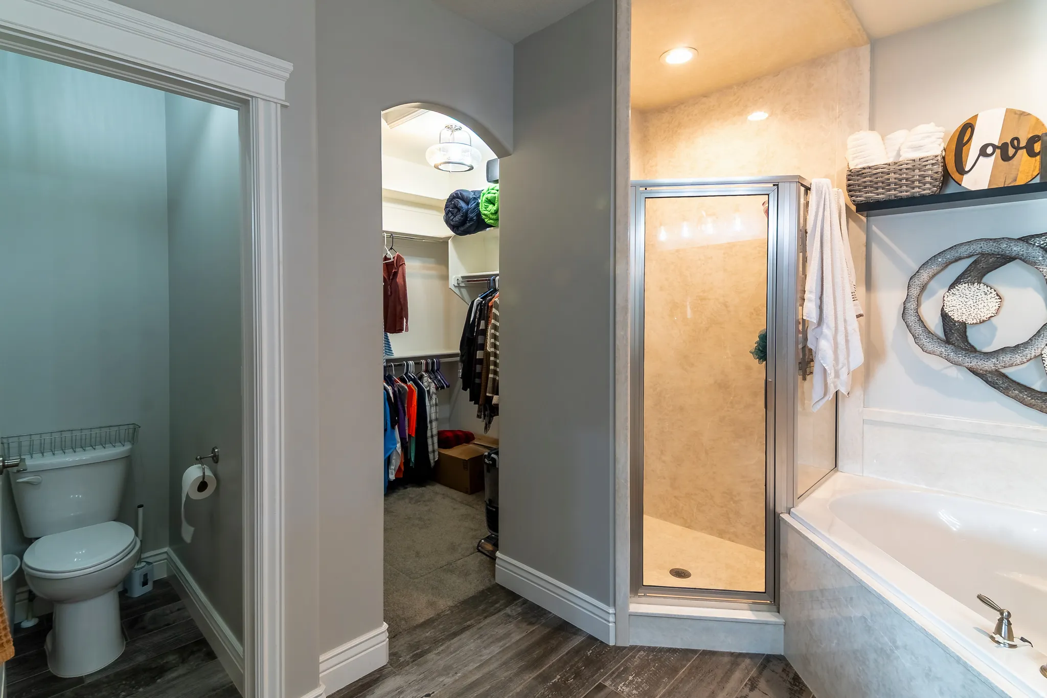 Bathroom with walk-in shower, soaking tub, private commode, and an arched entry to a walk-in closet