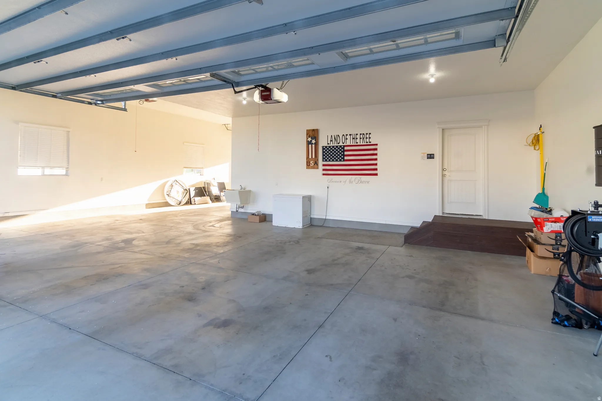 Spacious garage with concrete flooring, overhead lighting, and white walls