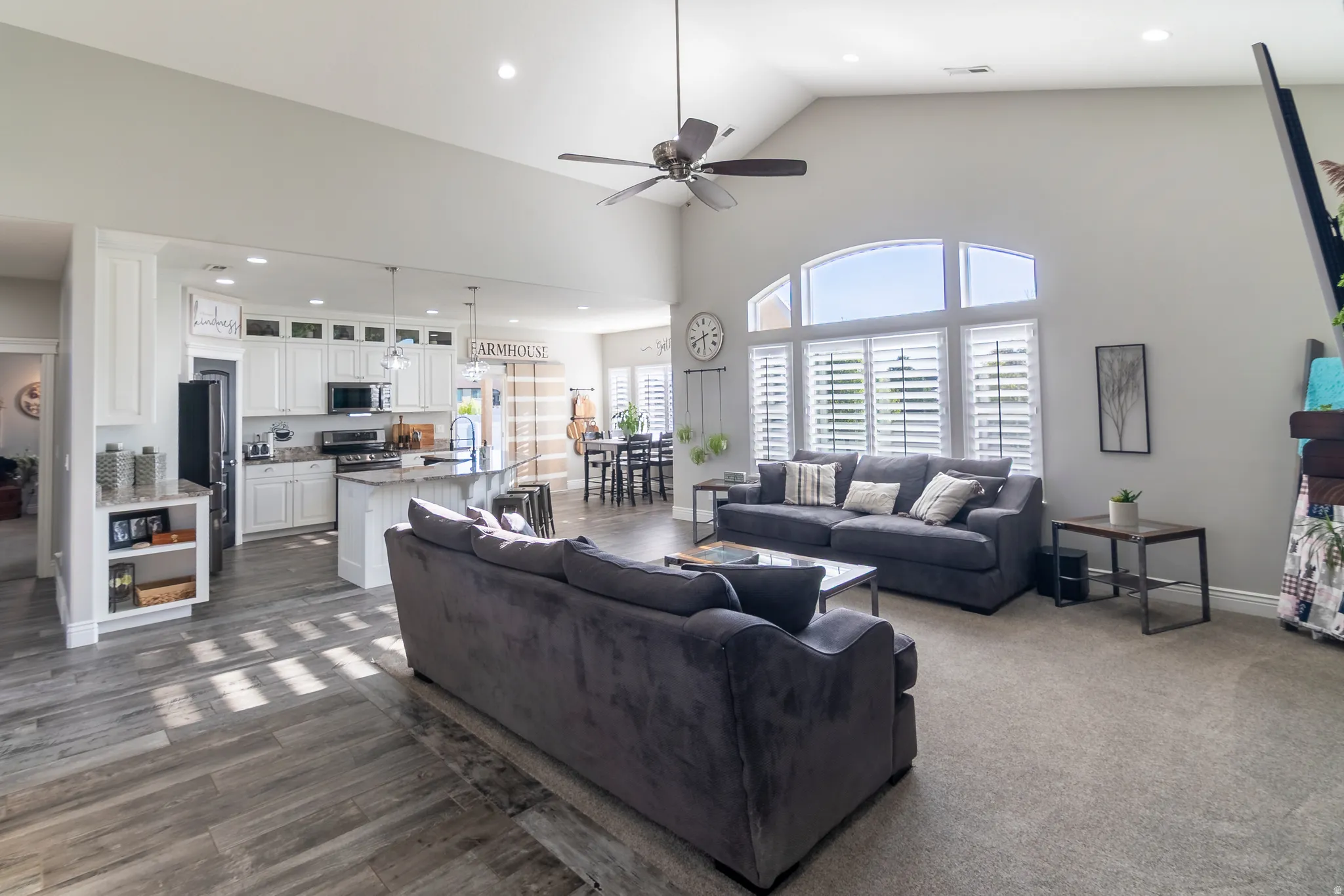 Open-concept living area featuring vaulted ceilings, recessed lighting, and a ceiling fan