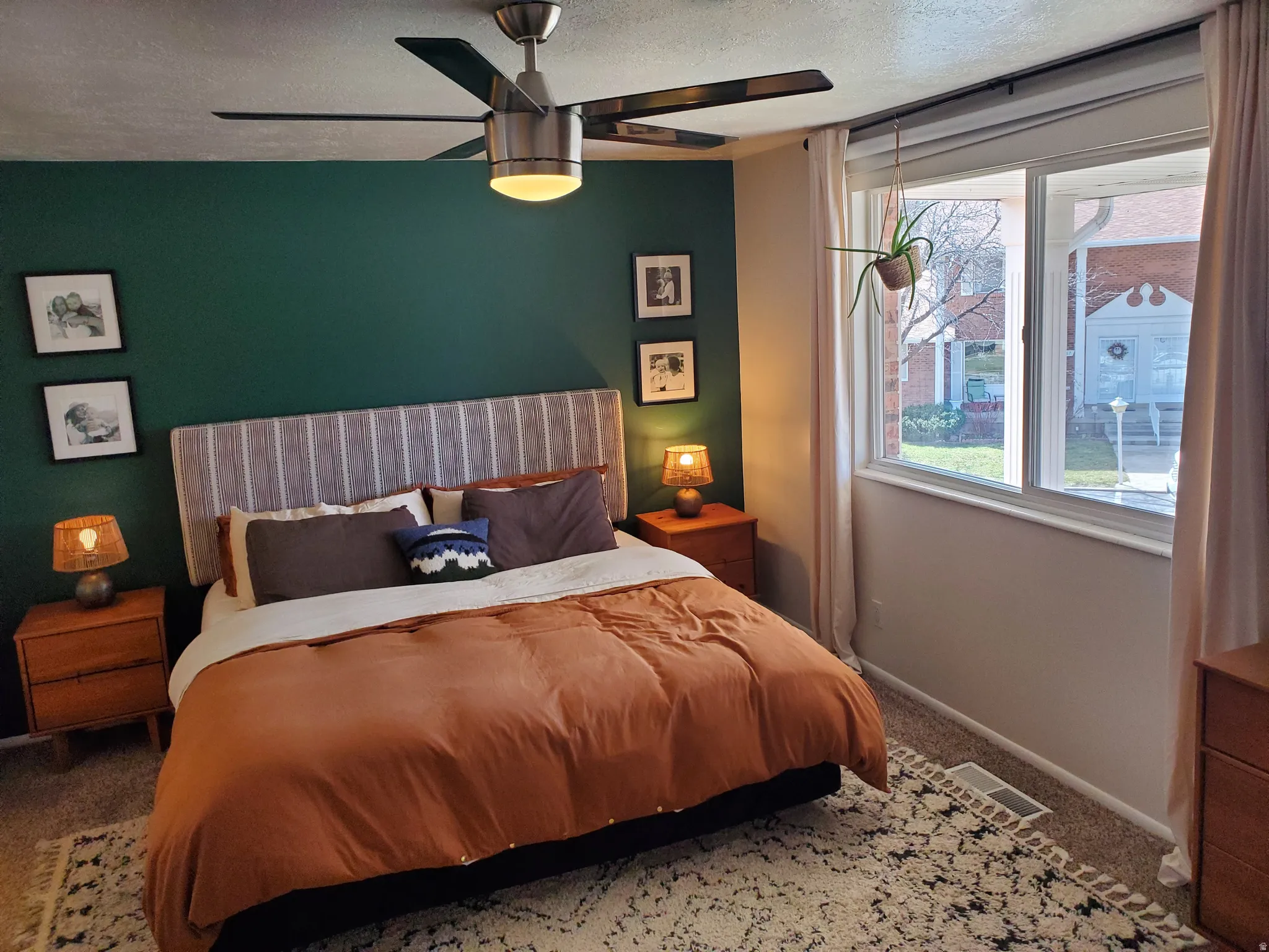 Bedroom featuring a ceiling fan with integrated lighting, a broad window providing ambient light, and carpeted flooring