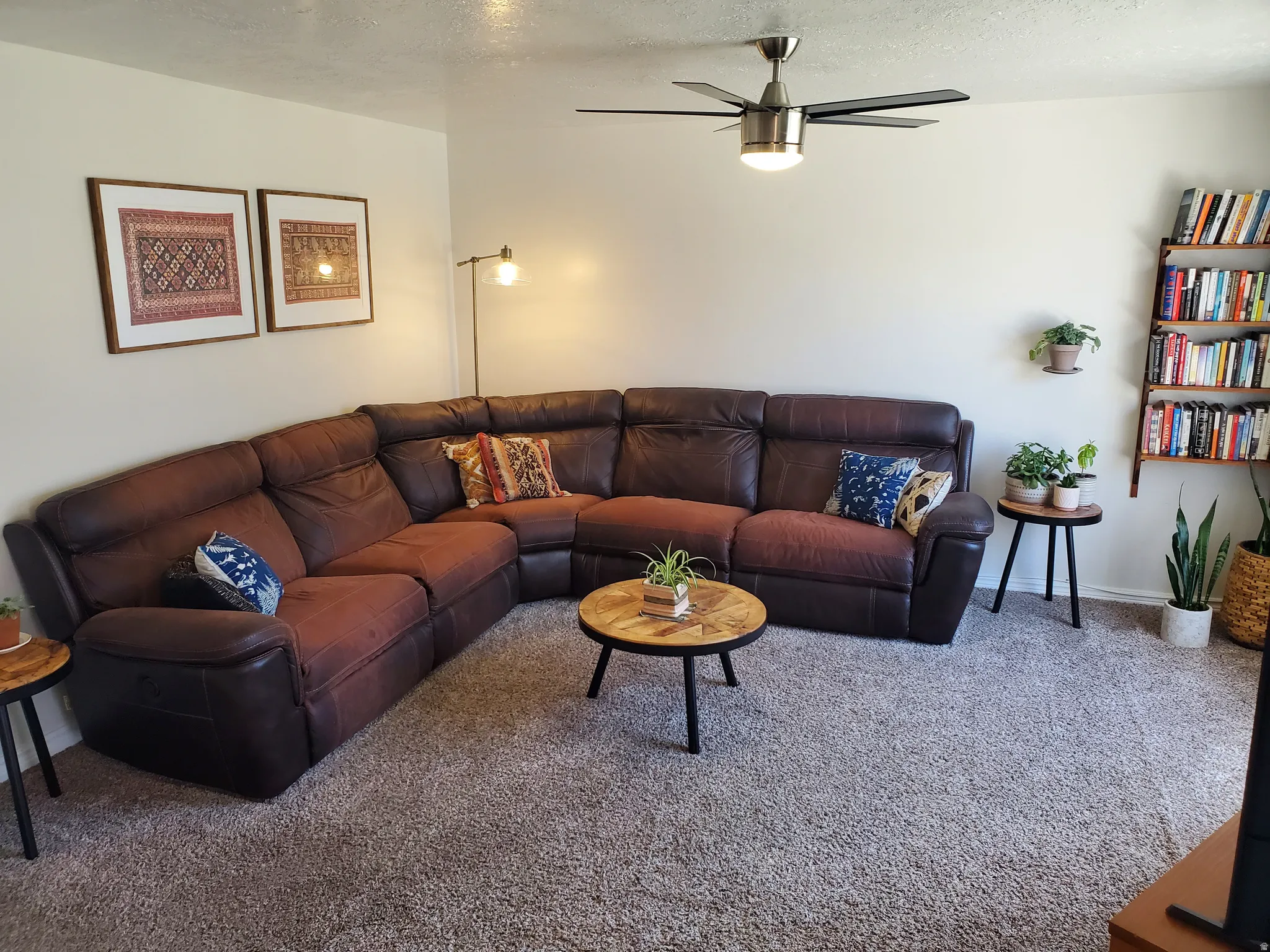 Carpeted living space featuring a ceiling fan with integrated lighting