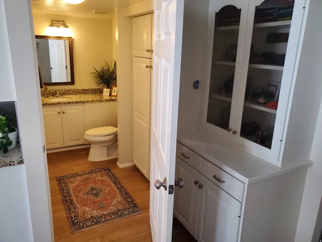 Bathroom featuring wood-finish flooring, a vanity with granite countertop and undermount sink, and a built-in linen cabinet