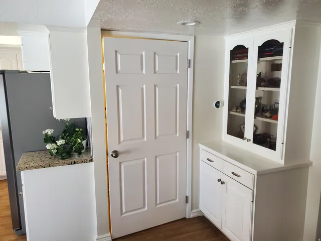 Built-in white cabinetry with glass display doors, neutral countertop, six-panel interior door, and recessed ceiling lighting