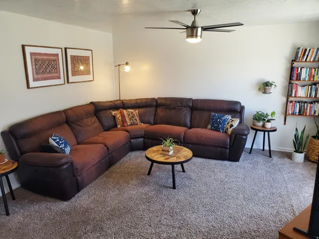 Carpeted living space featuring a ceiling fan with integrated lighting