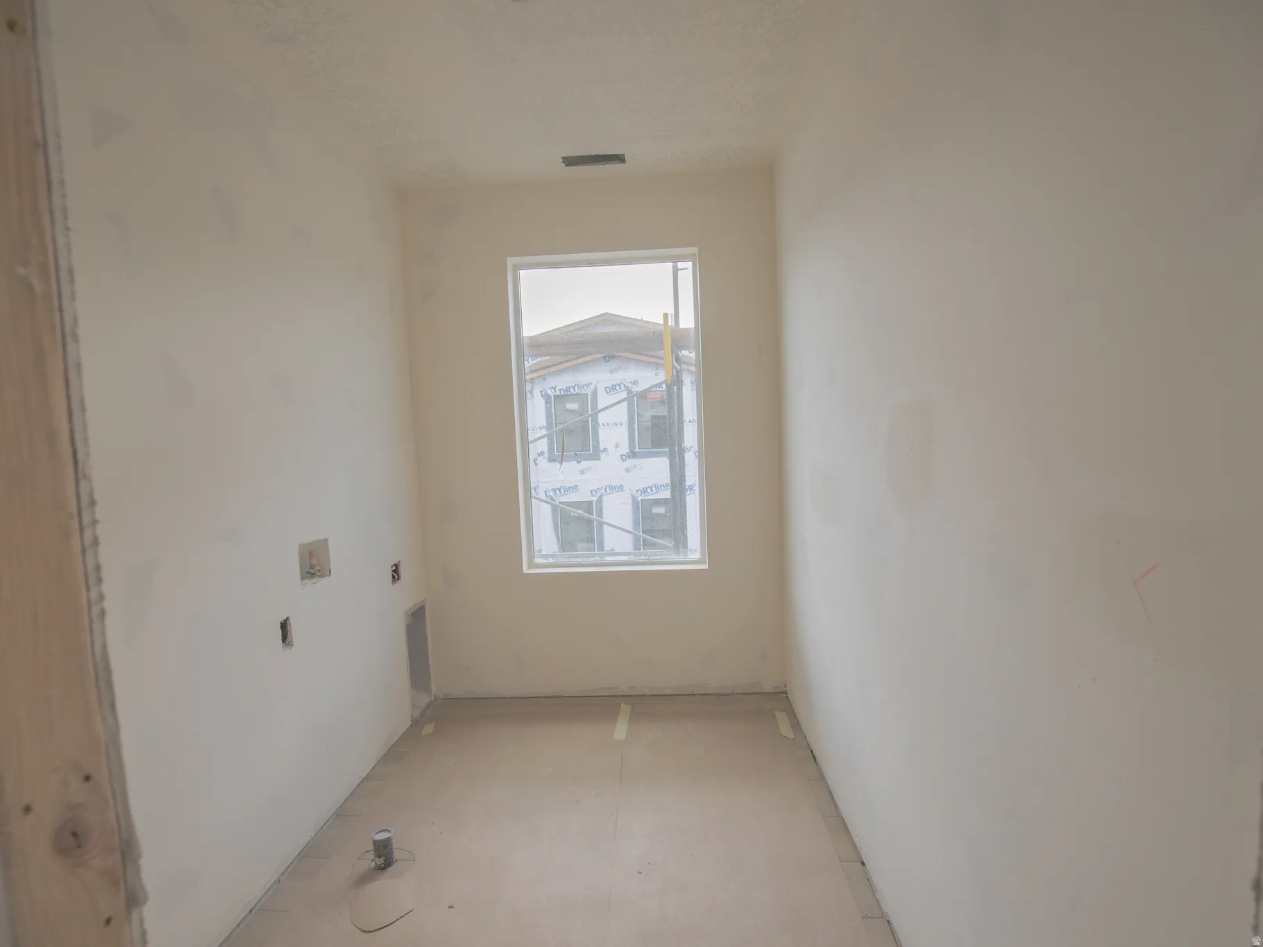 Light-filled room with a single window, smooth drywall, and unfinished flooring