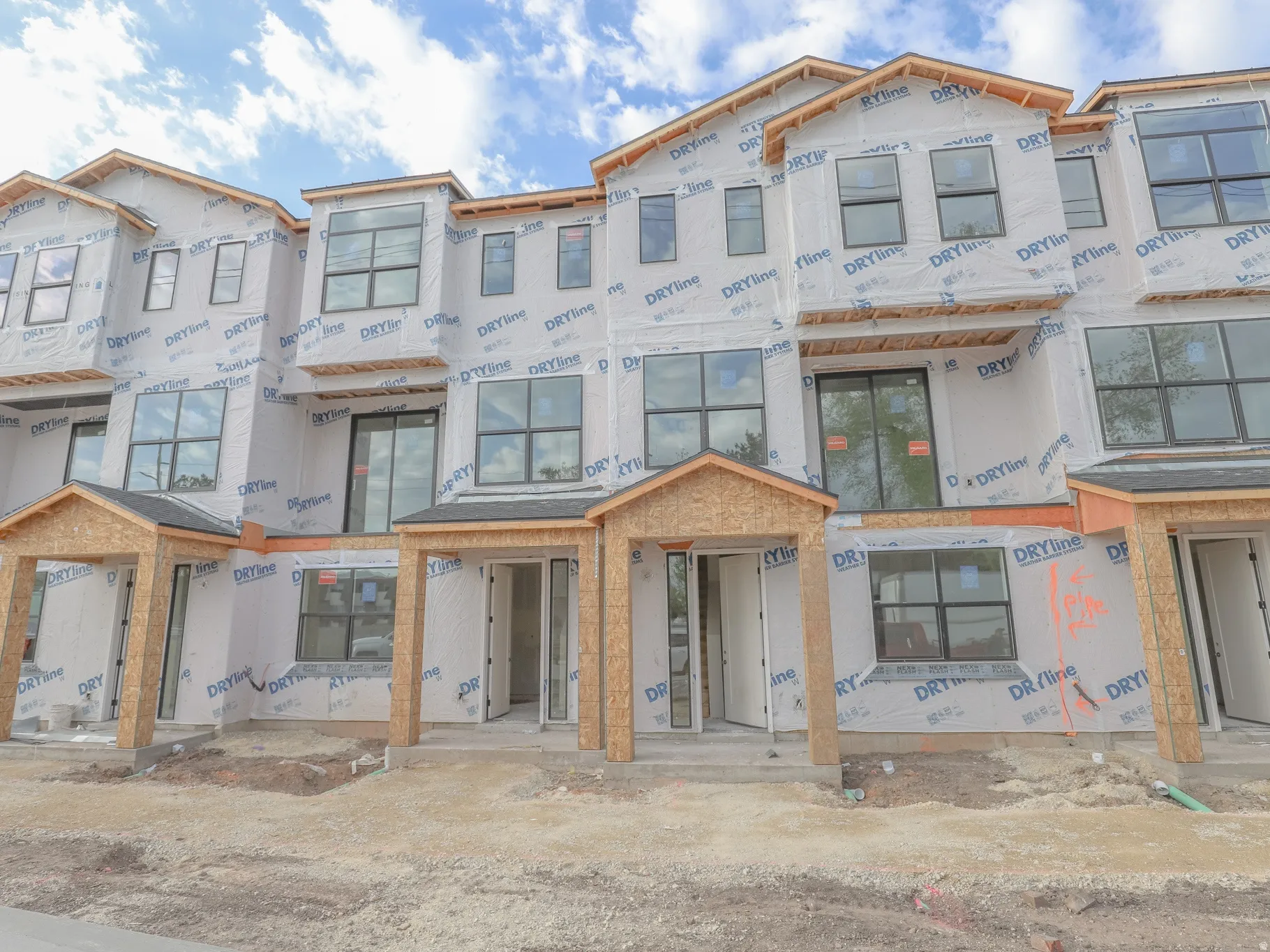 Modern multi-story construction featuring multiple window styles, covered entryways, and a multi-unit design