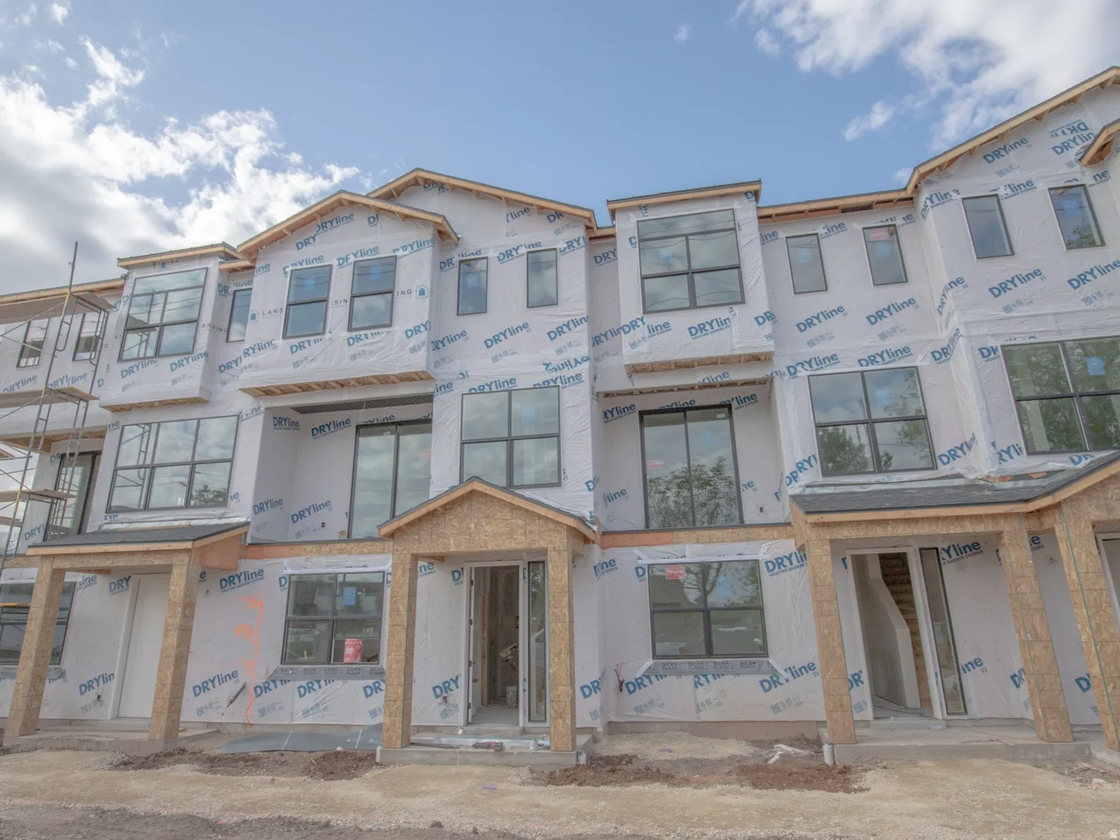 Modern multi-level townhome structure featuring multiple large windows, covered entryways, and a developing facade