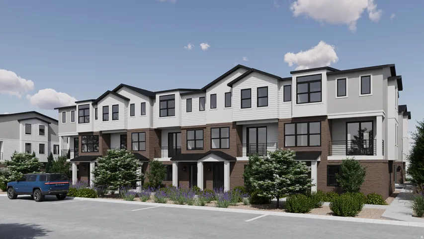 Modern townhome exterior featuring multi-toned siding, dark framed windows, and a brick base
