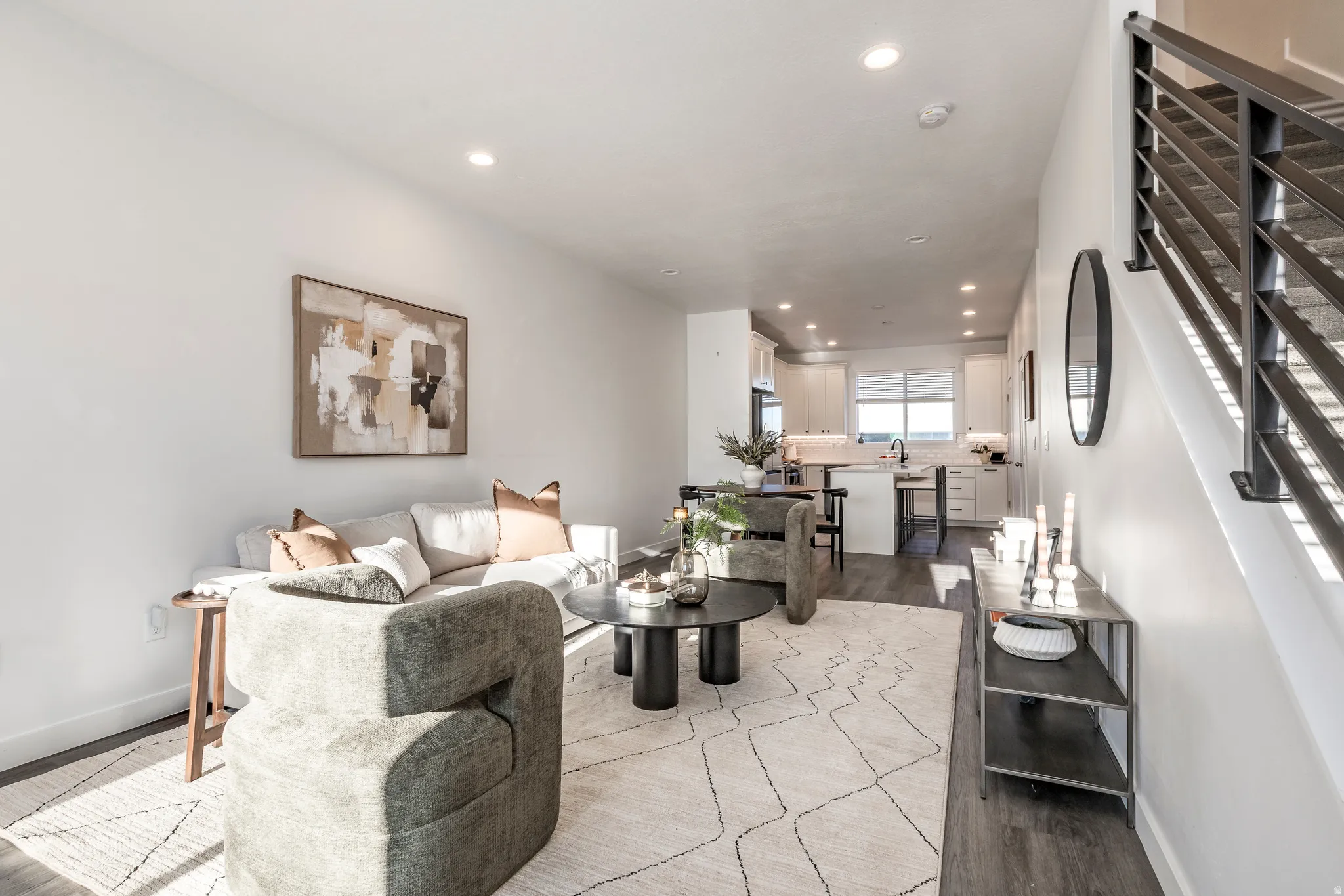 Open-concept living space featuring wood-finish flooring, recessed lighting, and a modern staircase with metal railings