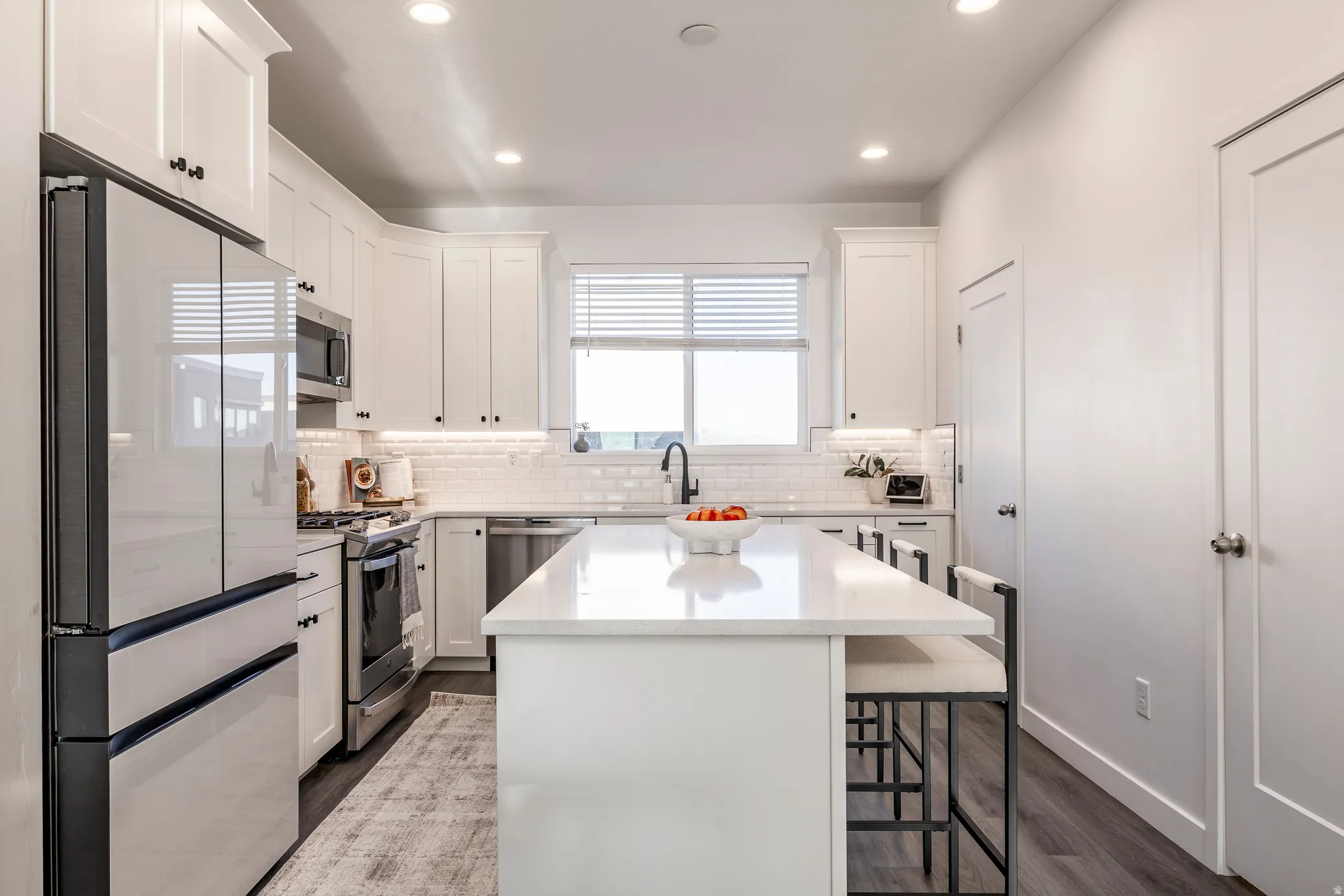 Modern kitchen featuring white shaker cabinetry, stainless steel appliances, a center island with countertop seating, and recessed lighting