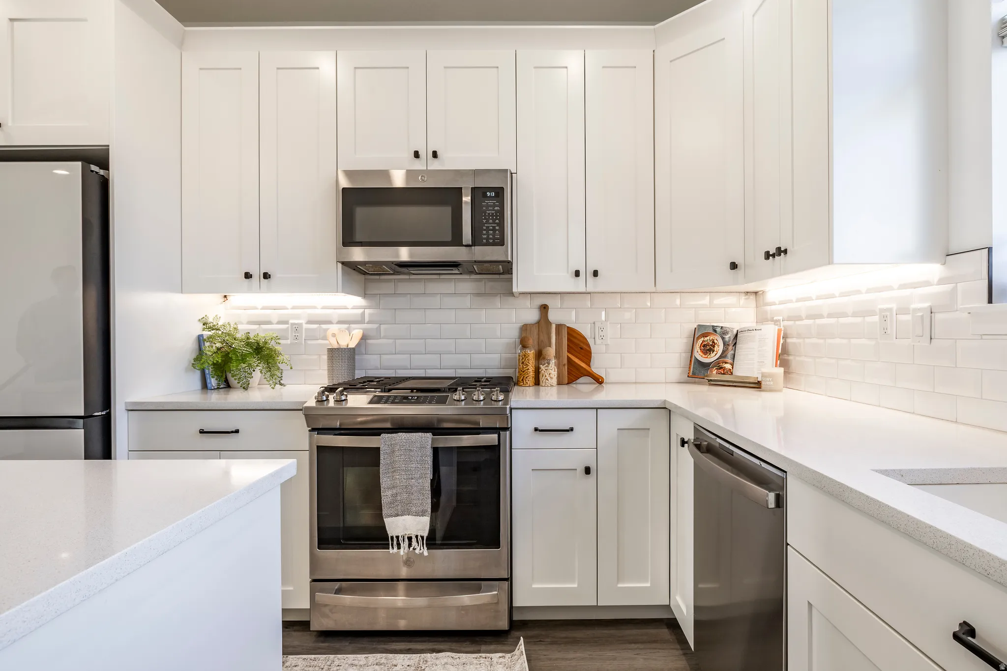 Modern kitchen featuring white shaker cabinetry, stainless steel appliances, a subway tile backsplash, and light-toned countertops