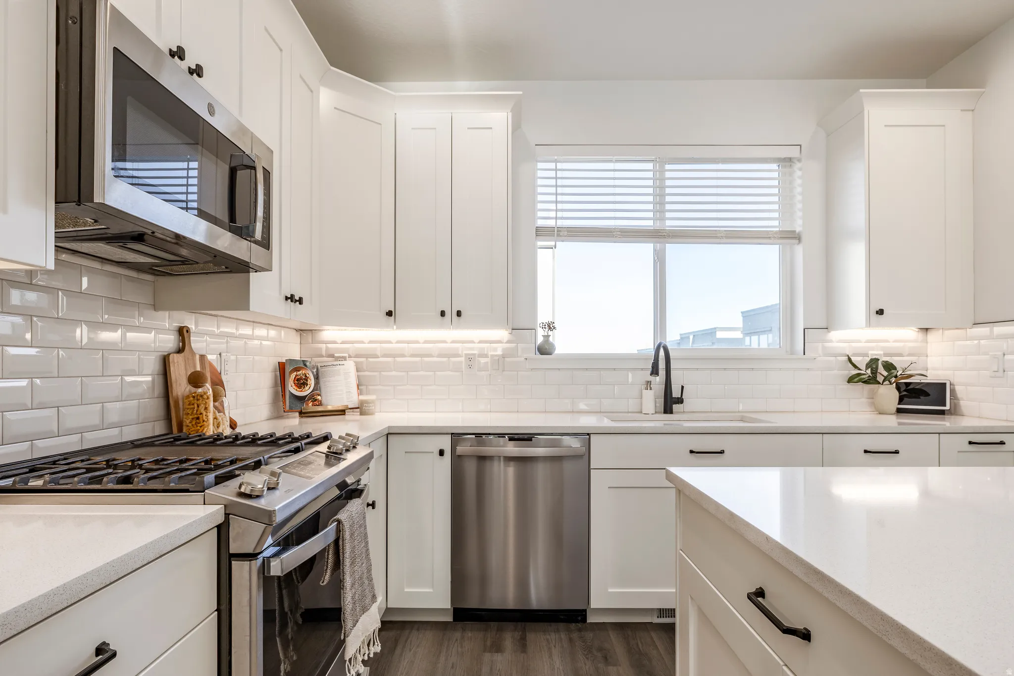 Modern kitchen featuring white shaker cabinetry, stainless steel appliances, a subway tile backsplash, and light-toned countertops