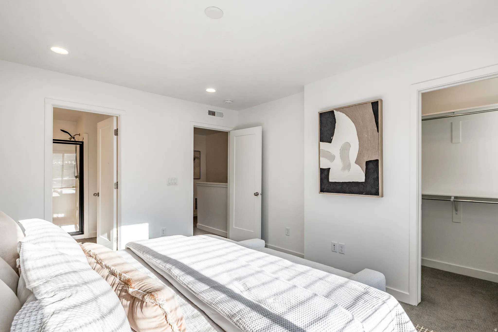 Bright bedroom featuring recessed lighting, white walls, carpeted flooring, and a built-in closet with shelving