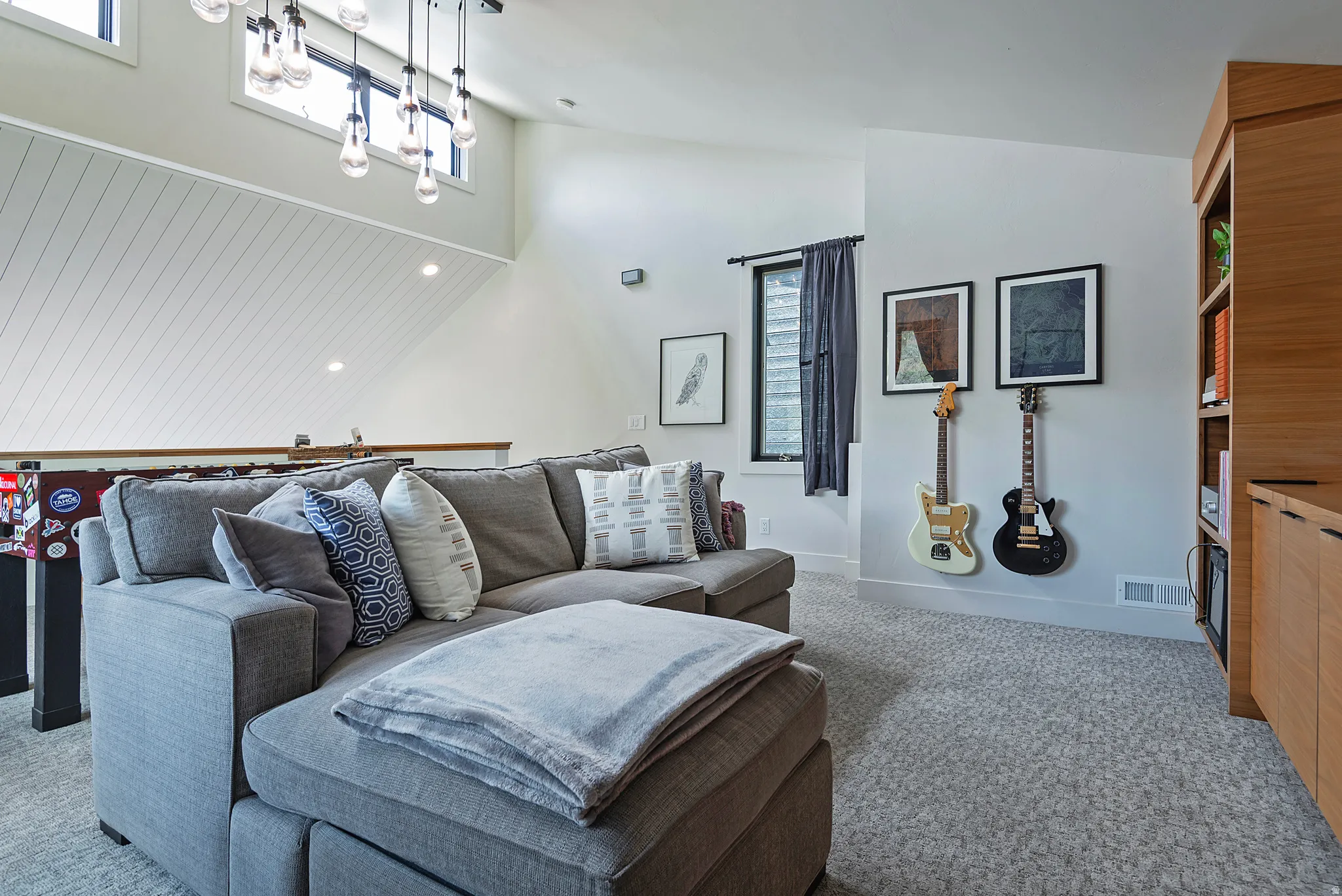 Carpeted bonus room featuring a built-in wood-finish shelving unit, high ceilings, and clerestory windows