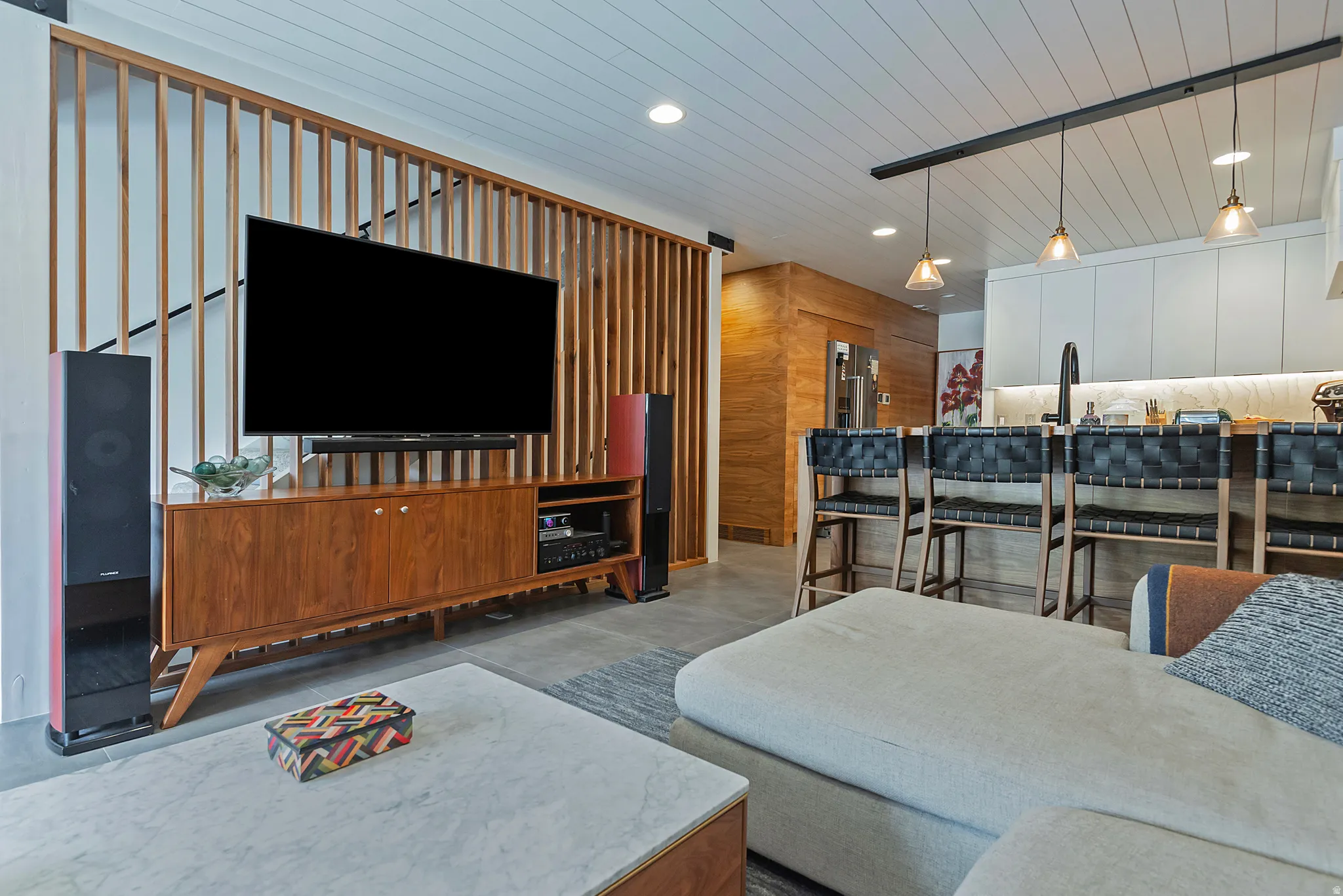 Open-concept living space featuring a wood-slat room divider, shiplap ceiling, and wood-finish flooring