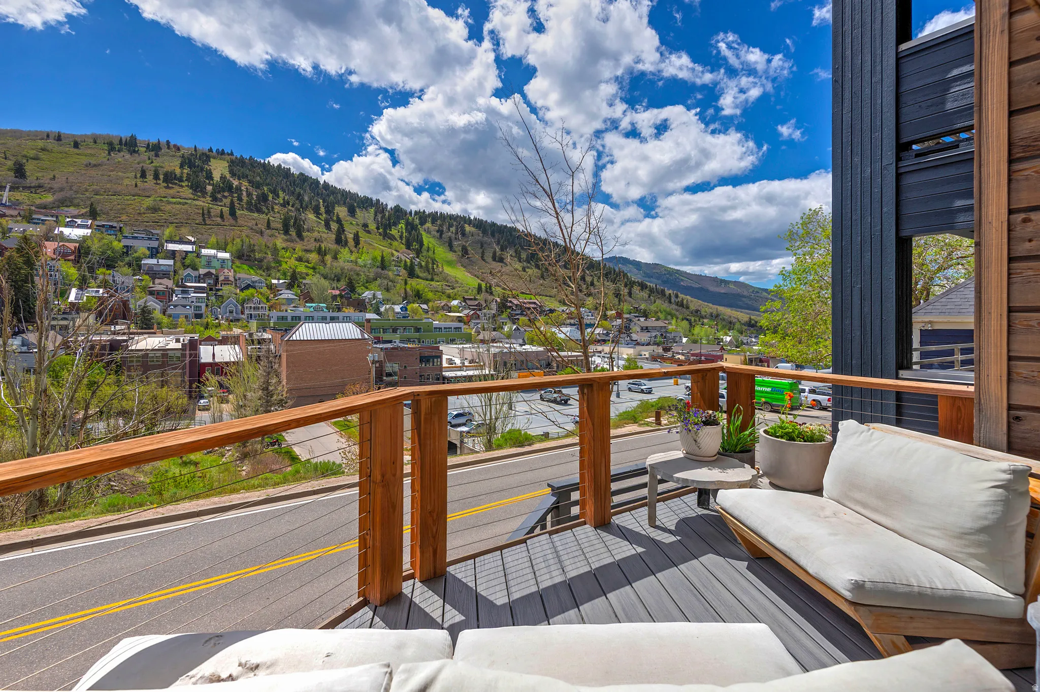 Spacious outdoor deck featuring gray composite decking, wood-toned railings with cable infill, and dark vertical siding