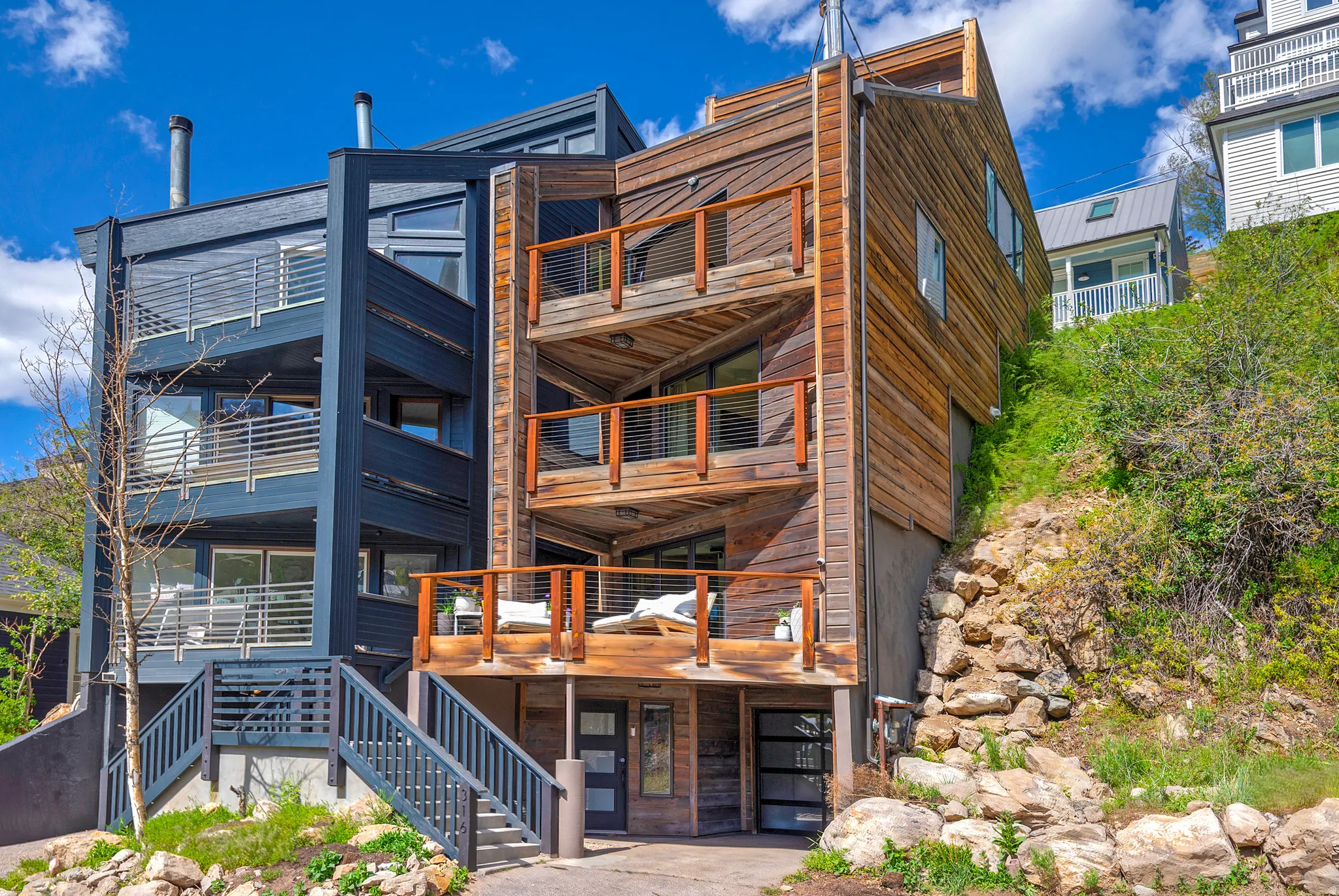 Contemporary multi-level residence featuring natural wood siding and a contrasting dark exterior