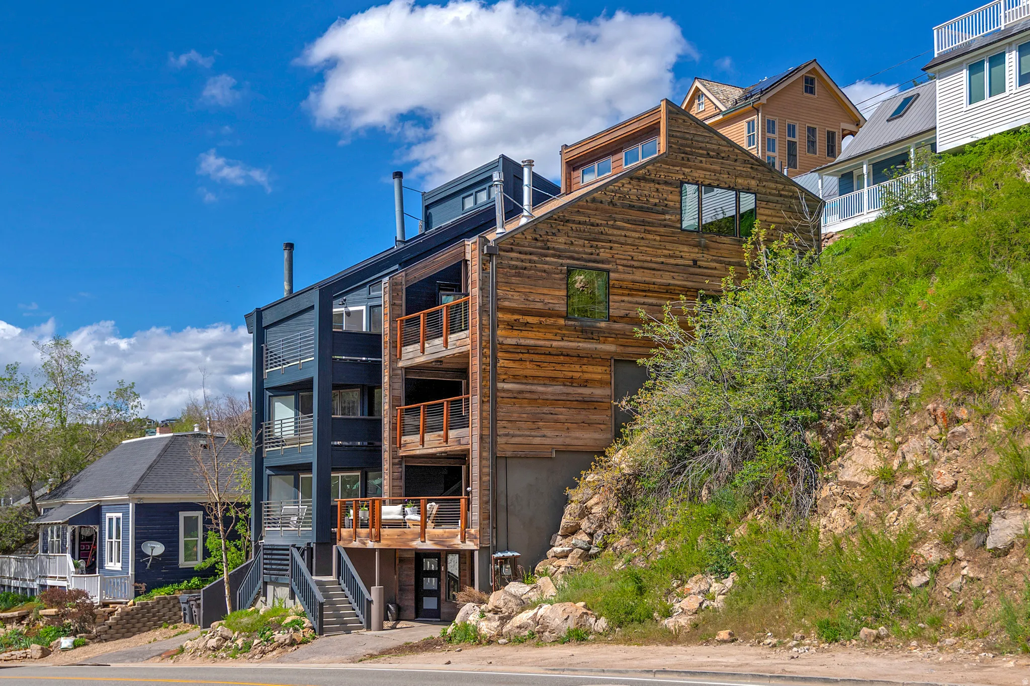 Contemporary multi-level exterior featuring dark paneled siding and natural wood cladding