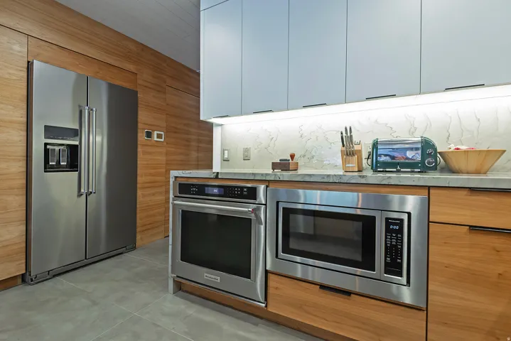 Modern kitchen featuring a stainless steel side-by-side refrigerator, built-in stainless steel microwave, and built-in stainless steel oven