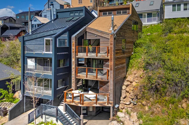 Contemporary multi-level residence featuring dark vertical siding and a metal roof