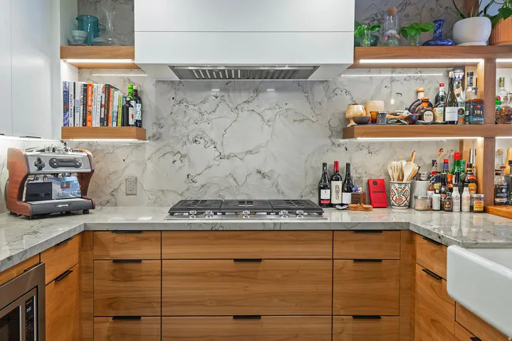 Contemporary kitchen featuring wood-finish cabinetry, light-toned countertops, and a full-height backsplash