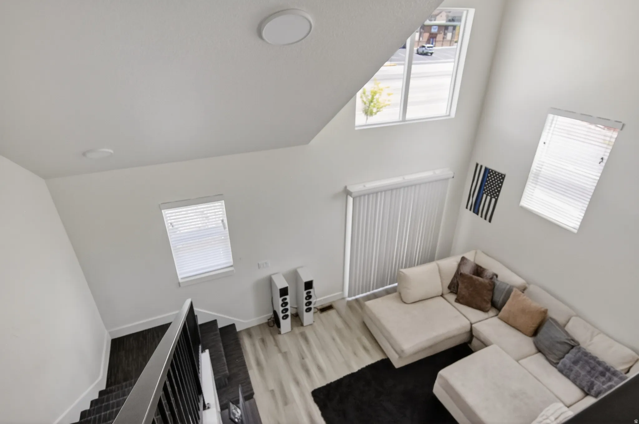 Soaring ceiling featuring multiple windows with blinds, recessed lighting, and wood-finish flooring