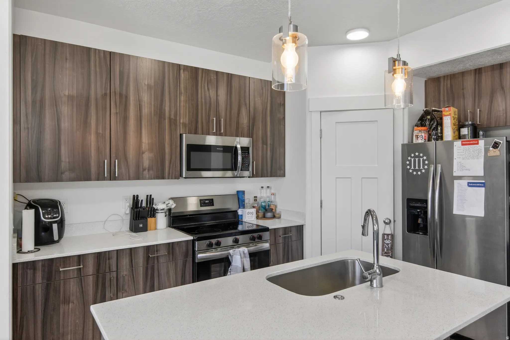 Kitchen featuring wood-finish cabinetry, stainless steel appliances, and quartz countertops