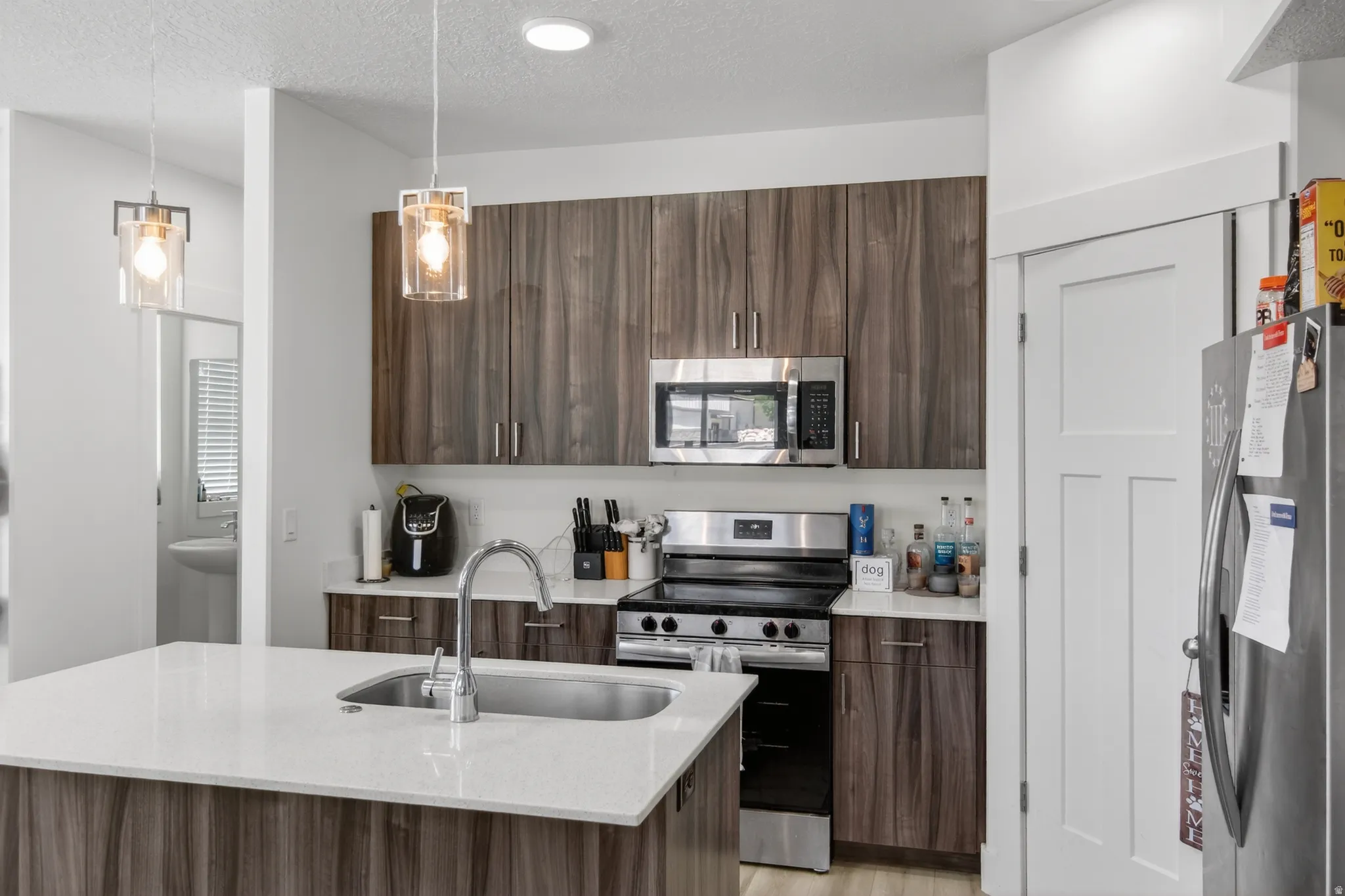 Modern kitchen featuring wood-finish cabinetry, stainless steel appliances, and a central island with an undermount sink