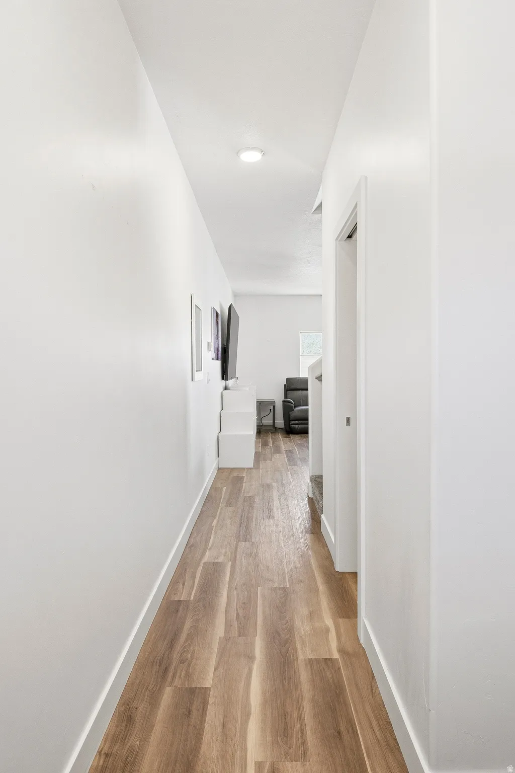 Bright hallway featuring wood-finish flooring, white baseboards, and overhead recessed lighting