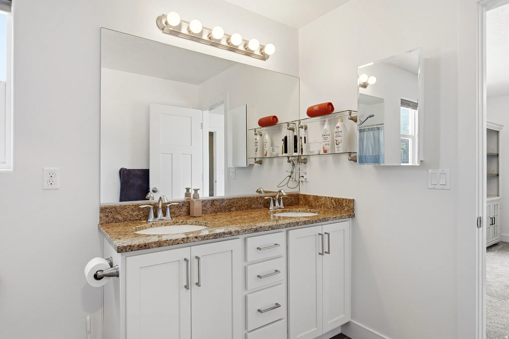 Dual vanity with a granite countertop and undermount sinks, featuring white cabinetry with silver-tone hardware