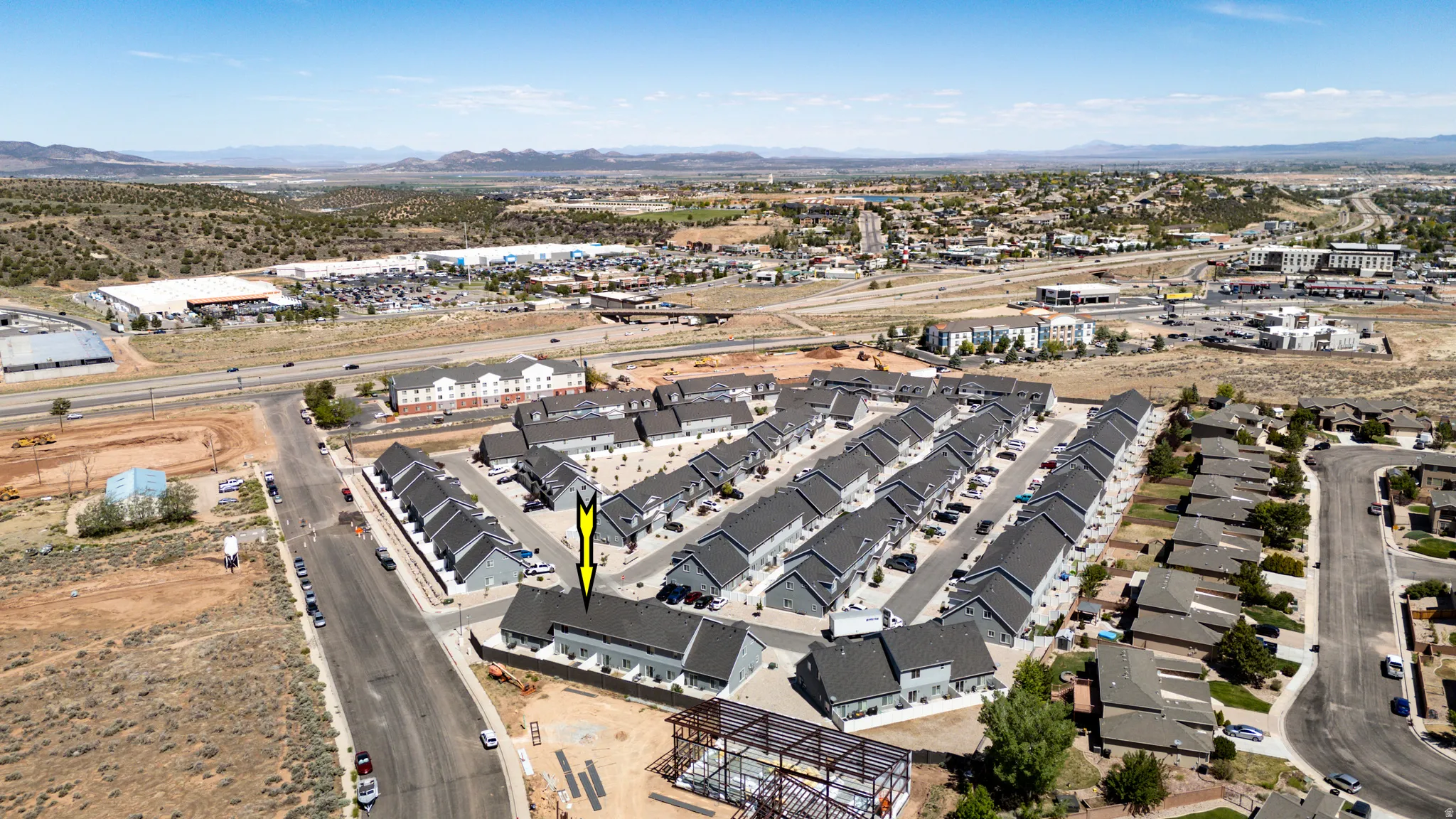 Aerial overview showcasing a community of multiple residential structures with dark gray roofs and light-colored siding