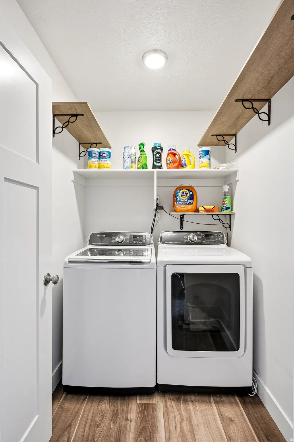 Dedicated laundry area featuring wood-finish flooring, white walls, and built-in shelving