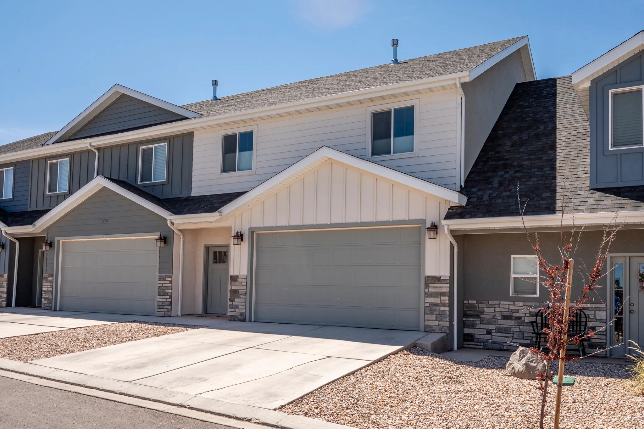 Contemporary townhome exterior featuring dual-tone siding, stone accents, and a two-car garage