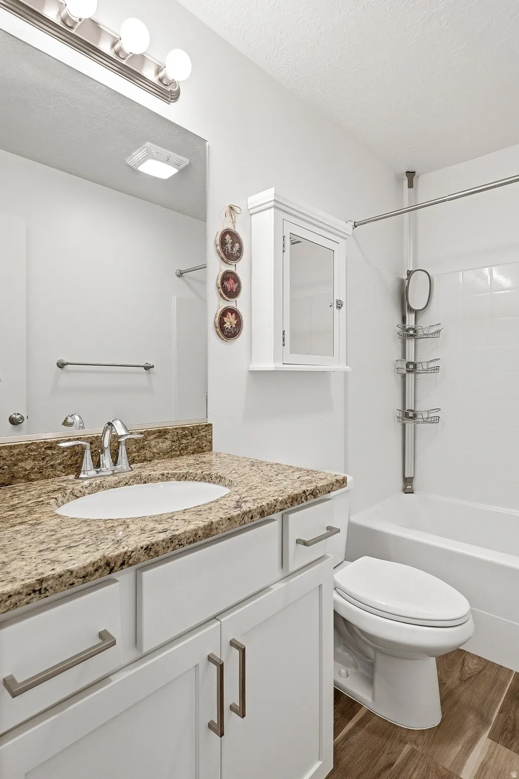 Vanity featuring a stone countertop with an undermount sink, white cabinetry with brushed nickel hardware, and a chrome faucet