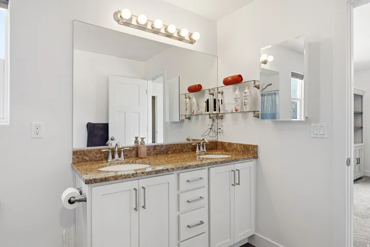 Dual vanity with a granite countertop and undermount sinks, featuring white cabinetry with silver-tone hardware