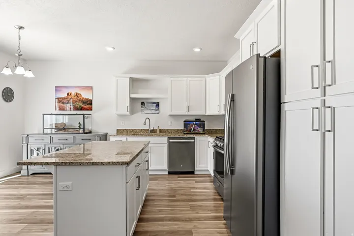 Kitchen featuring white cabinetry, granite countertops, and wood-finish flooring
