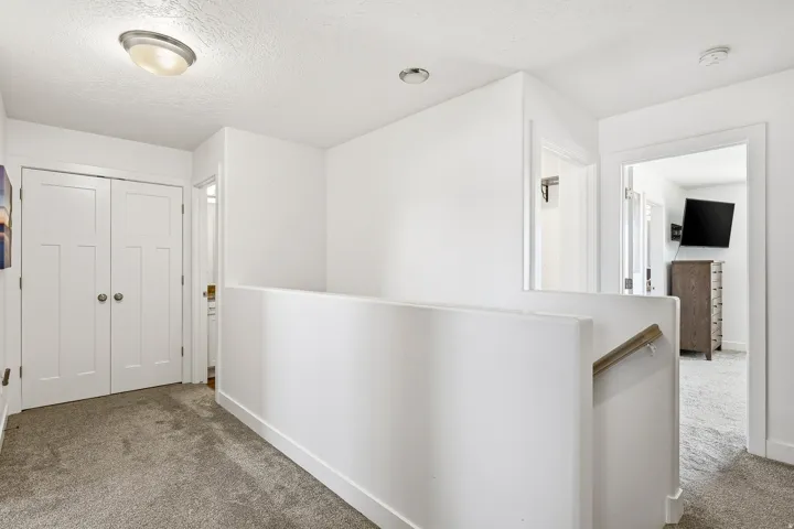 Upper-level hallway featuring a carpeted floor, white walls, and a contemporary flush-mount ceiling fixture
