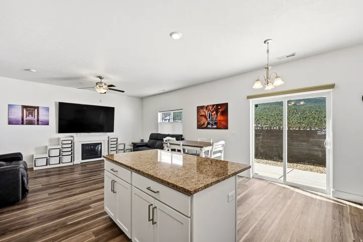 Kitchen island with a granite-finish countertop, white cabinetry, and brushed nickel hardware