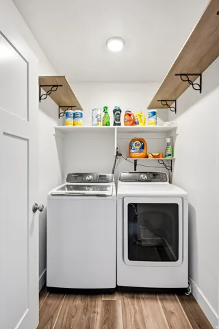 Dedicated laundry area featuring wood-finish flooring, white walls, and built-in shelving