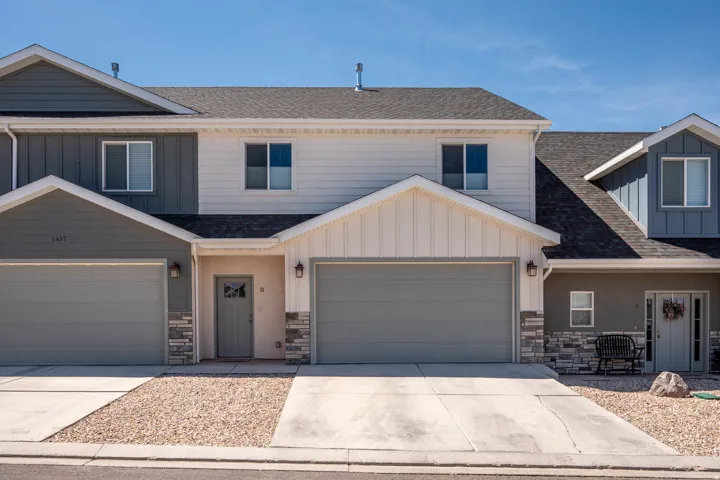 Contemporary townhome exterior featuring a two-car garage, stone accents, and varied siding